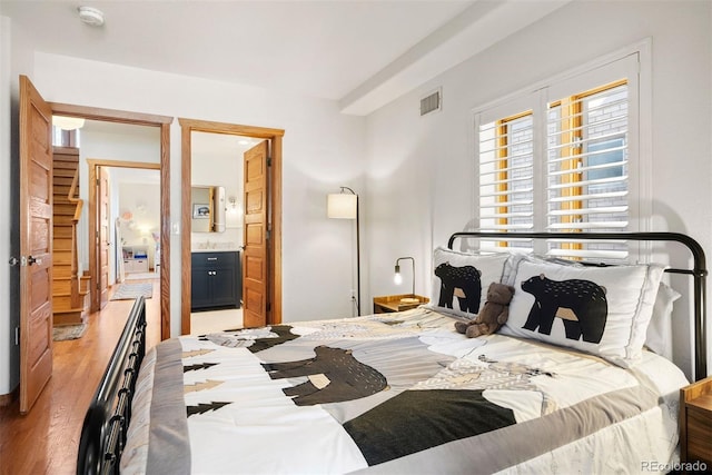 bedroom featuring ensuite bathroom and light hardwood / wood-style flooring