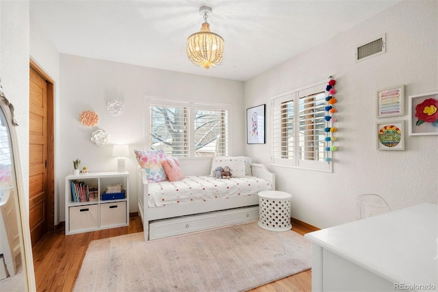 bedroom featuring light hardwood / wood-style flooring and an inviting chandelier