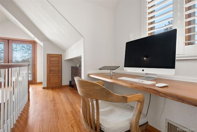 office with light wood-type flooring, vaulted ceiling, a healthy amount of sunlight, and a textured ceiling