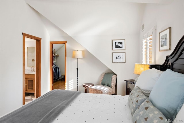 bedroom with a spacious closet, lofted ceiling, ensuite bath, sink, and a closet