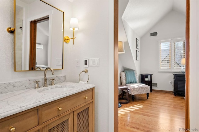 bathroom featuring hardwood / wood-style flooring, vaulted ceiling, and vanity