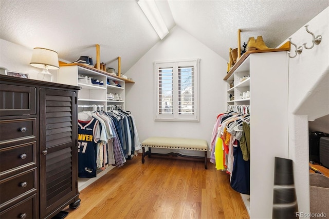 walk in closet with light wood-type flooring and lofted ceiling