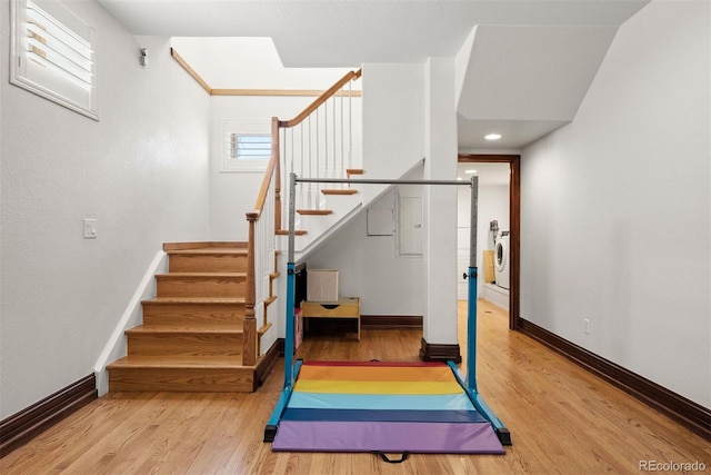 exercise area with light wood-type flooring and washer / clothes dryer