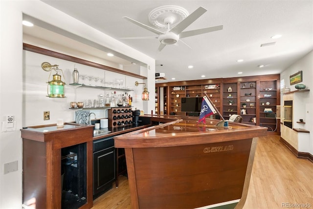 bar with sink, light hardwood / wood-style floors, a textured ceiling, and ceiling fan