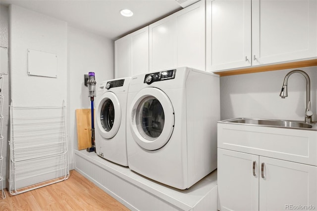 washroom with sink, light hardwood / wood-style flooring, cabinets, and washer and dryer