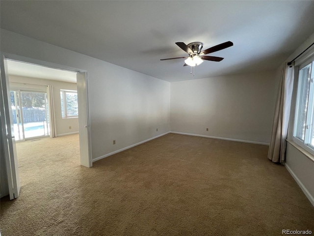 empty room with light colored carpet, ceiling fan, and a healthy amount of sunlight