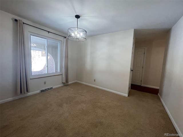 carpeted spare room featuring an inviting chandelier