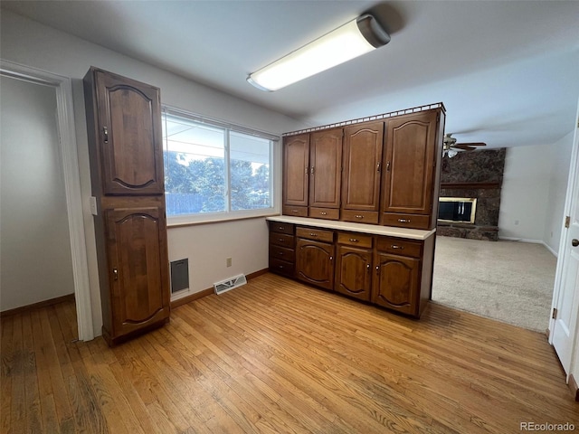 kitchen with light hardwood / wood-style flooring, dark brown cabinetry, and a fireplace