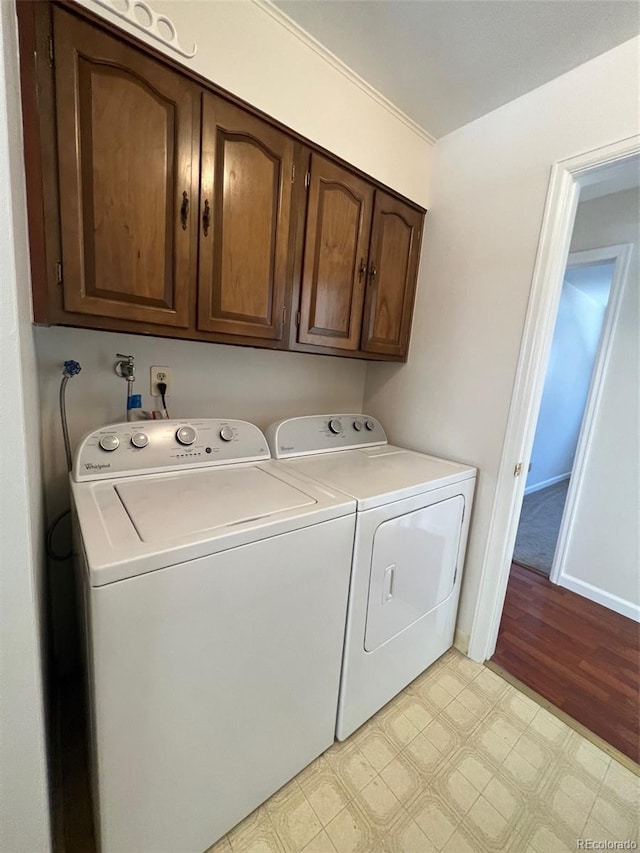 laundry area with cabinets, light hardwood / wood-style floors, washer hookup, and washing machine and clothes dryer