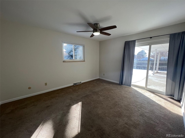 spare room featuring ceiling fan, plenty of natural light, and dark carpet