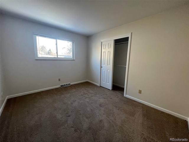 unfurnished bedroom featuring a closet and dark carpet