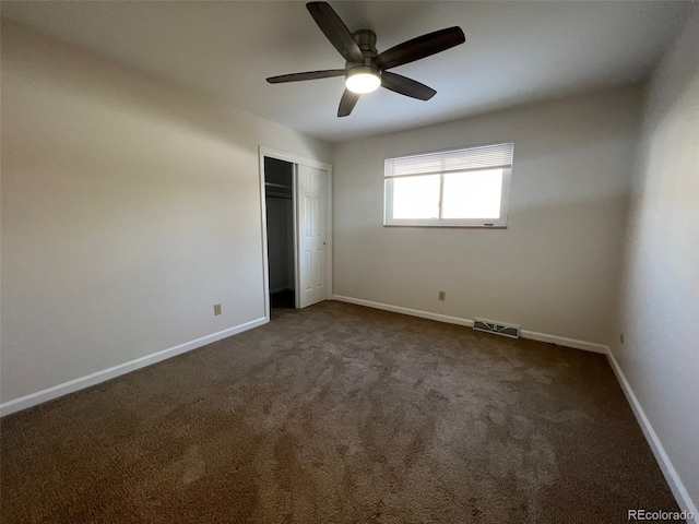 unfurnished bedroom with a closet, ceiling fan, and dark carpet