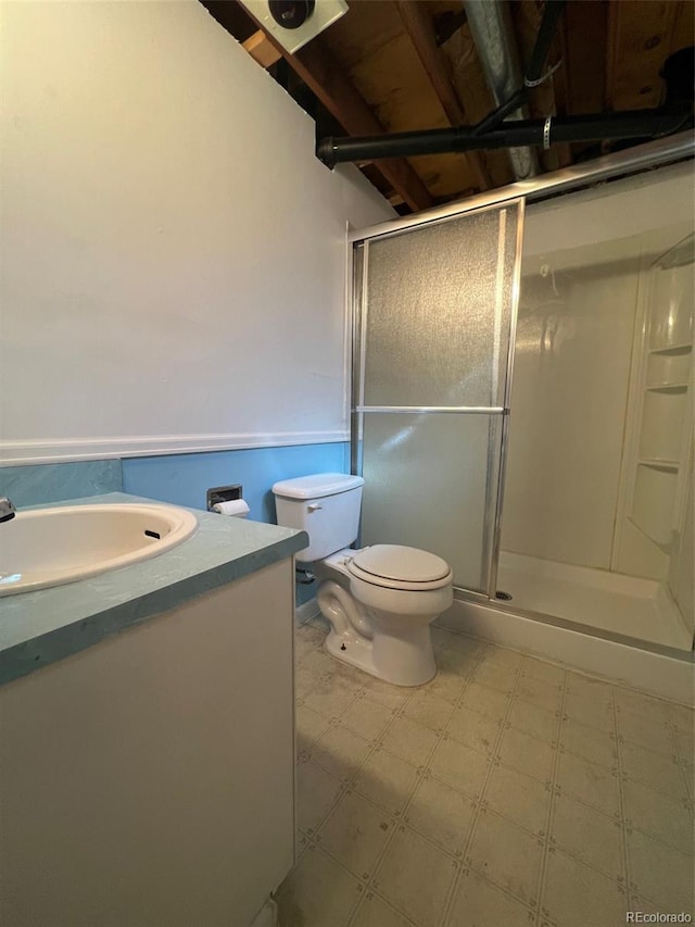 bathroom featuring a shower with door, toilet, tile floors, and vanity