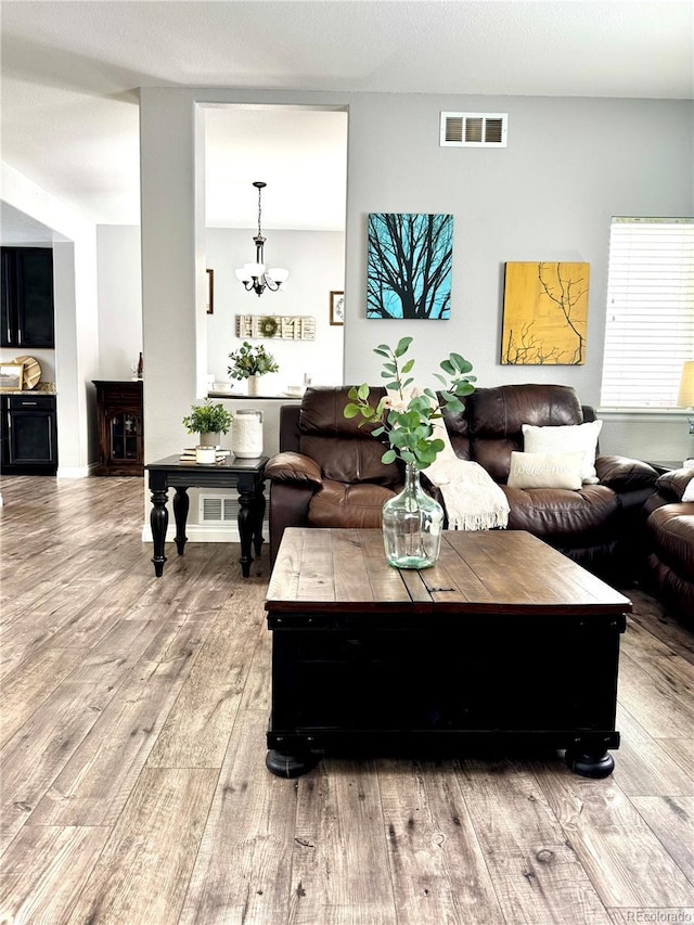 living room with an inviting chandelier and light hardwood / wood-style flooring