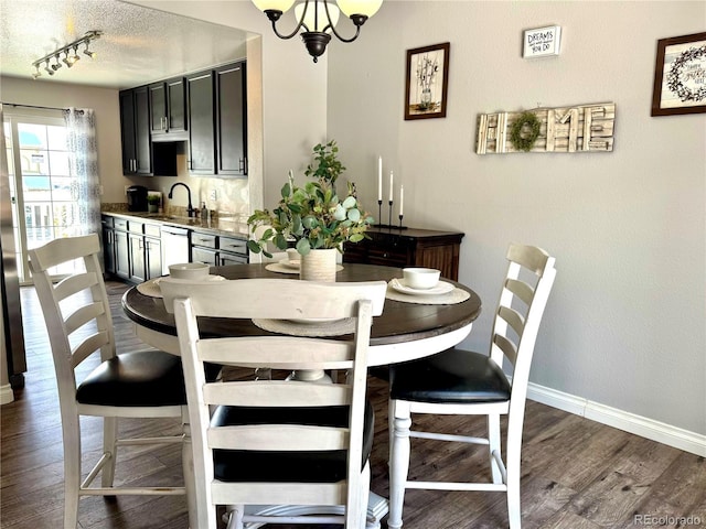 dining room with sink, dark wood-type flooring, a textured ceiling, and an inviting chandelier