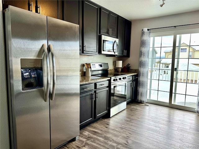 kitchen featuring light wood-type flooring, stainless steel appliances, and light stone countertops