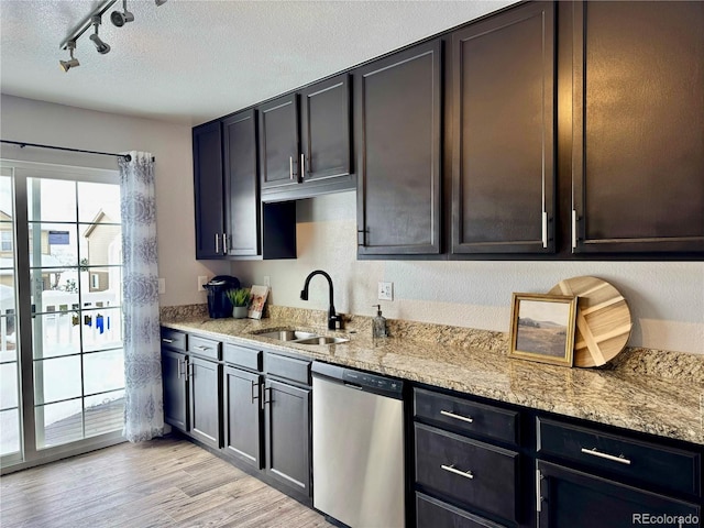 kitchen featuring dishwasher, sink, light stone countertops, track lighting, and light hardwood / wood-style floors