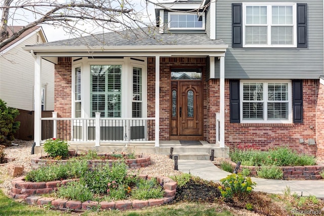property entrance with brick siding, a porch, and roof with shingles