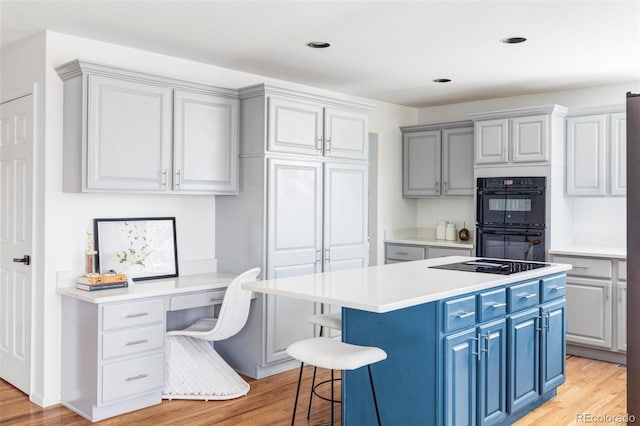 kitchen with black appliances, blue cabinets, light wood-style flooring, light countertops, and recessed lighting