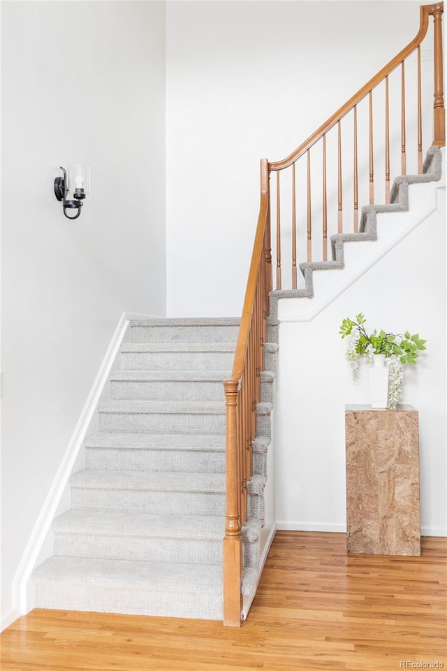 staircase featuring wood finished floors and baseboards