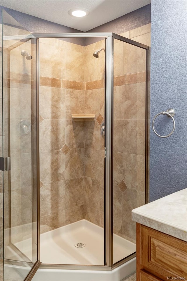 bathroom with a stall shower, a textured wall, vanity, and recessed lighting