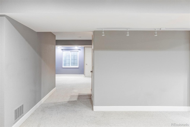 hall with rail lighting, carpet, and baseboards