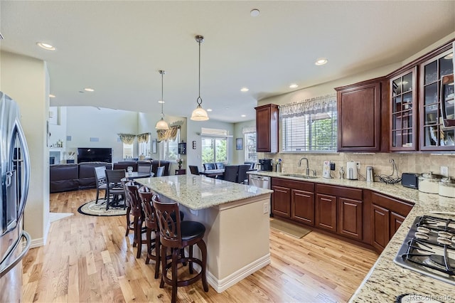 kitchen with light hardwood / wood-style flooring, a center island, tasteful backsplash, and a breakfast bar area