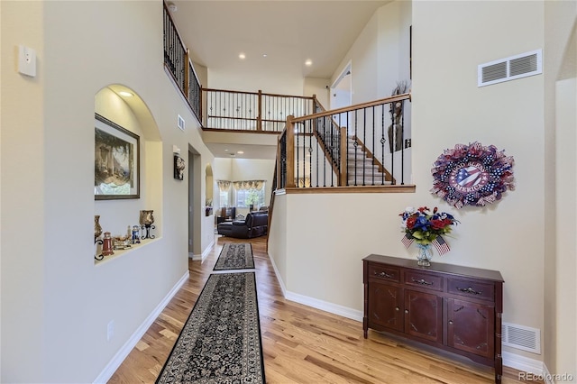 entryway featuring a towering ceiling and light hardwood / wood-style flooring