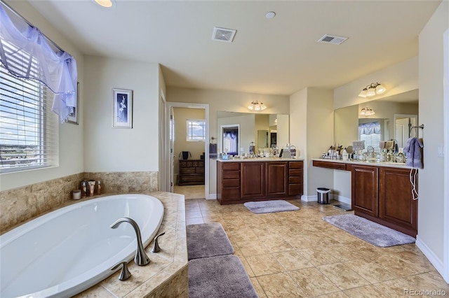 bathroom featuring tiled tub, vanity, and tile patterned flooring