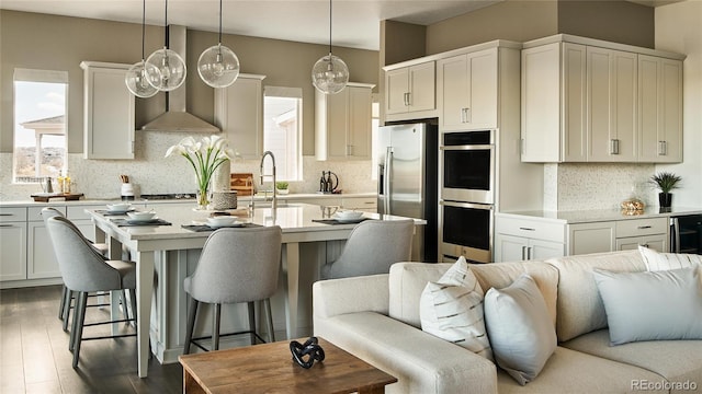 16655 W 93rd Pl, Arvada, CO 80007 - kitchen featuring appliances with stainless steel finishes, open floor plan, healthy amount of natural light, and wall chimney range hood