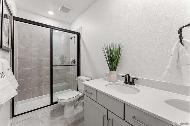16655 W 93rd Pl, Arvada, CO 80007 - full bathroom featuring a stall shower, toilet, tile patterned floors, vanity, and a textured wall