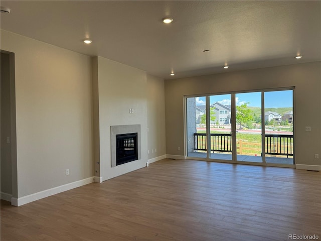 16655 W 93rd Pl, Arvada, CO 80007 - unfurnished living room featuring baseboards, wood finished floors, a glass covered fireplace, and recessed lighting