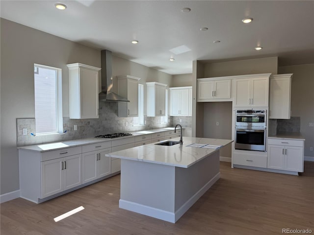 16655 W 93rd Pl, Arvada, CO 80007 - kitchen featuring wall chimney range hood, double oven, a sink, white cabinetry, and gas stovetop