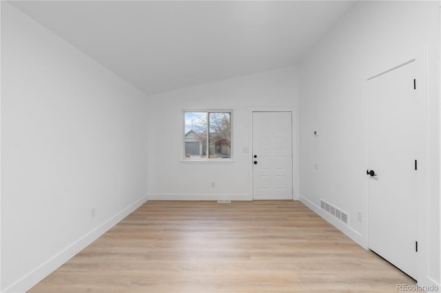 interior space with light wood finished floors, visible vents, baseboards, and vaulted ceiling