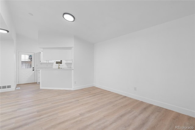 unfurnished living room with light wood finished floors, visible vents, and baseboards