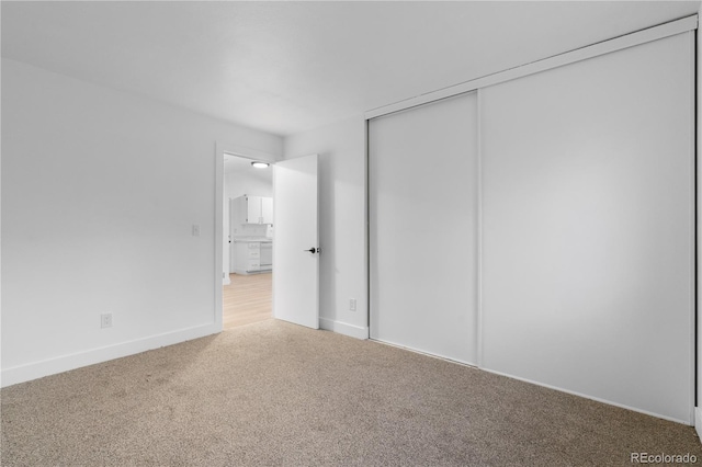 unfurnished bedroom with light carpet, baseboards, and a closet