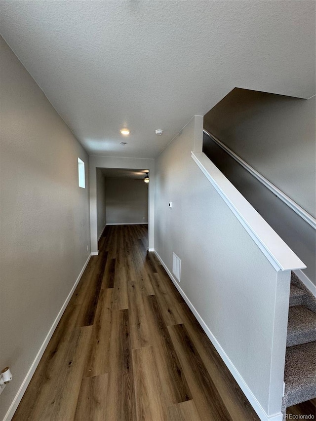 corridor with dark wood-type flooring and a textured ceiling