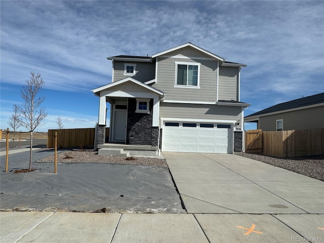 view of front facade with stone siding, concrete driveway, a garage, and fence