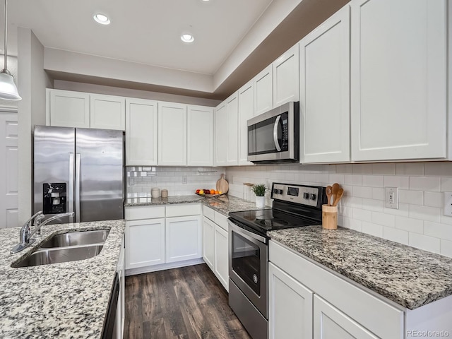 kitchen featuring stainless steel appliances, white cabinets, hanging light fixtures, and sink