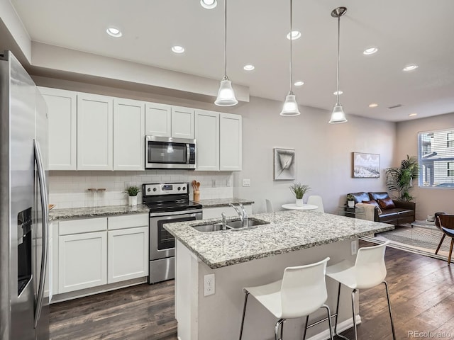 kitchen with decorative light fixtures, white cabinets, sink, and stainless steel appliances