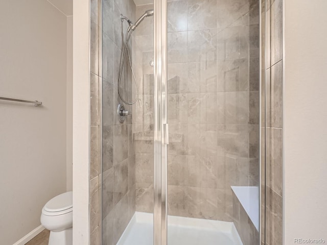 bathroom featuring toilet and a shower with shower door