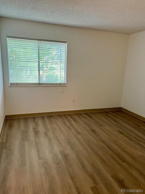 4400 S Quebec St Unit 102R, Denver, CO 80237 - unfurnished room with wood finished floors, a textured ceiling, and baseboards
