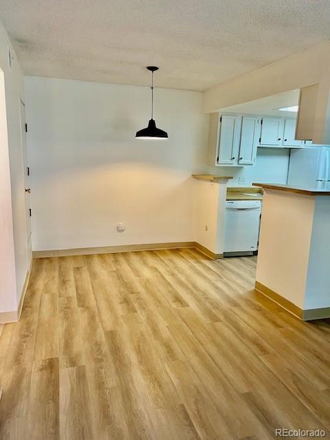 4400 S Quebec St Unit 102R, Denver, CO 80237 - kitchen with white dishwasher, light wood finished floors, a textured ceiling, decorative light fixtures, and blue cabinets