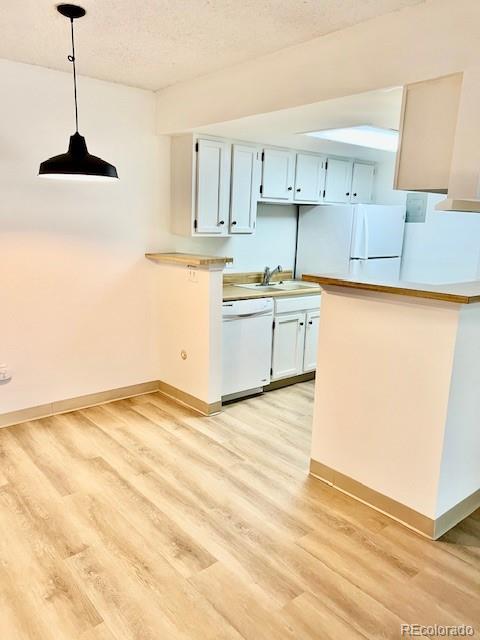 4400 S Quebec St Unit 102R, Denver, CO 80237 - kitchen featuring dishwasher, light wood-type flooring, decorative light fixtures, light countertops, and a peninsula