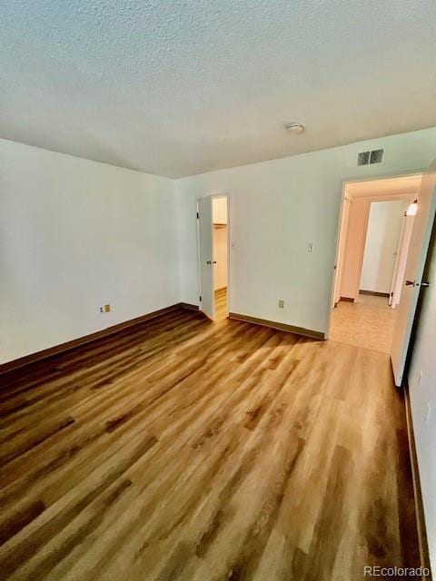 4400 S Quebec St Unit 102R, Denver, CO 80237 - empty room with wood finished floors, a smoke detector, and a textured ceiling