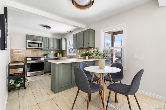 kitchen with a healthy amount of sunlight, stainless steel appliances, kitchen peninsula, and decorative backsplash