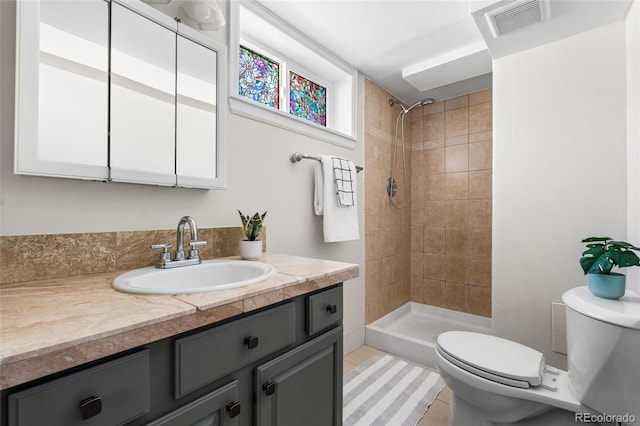 bathroom featuring vanity, toilet, tile patterned flooring, and a tile shower