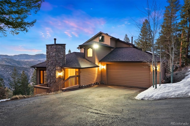 view of front of house featuring a garage, driveway, a shingled roof, and a mountain view