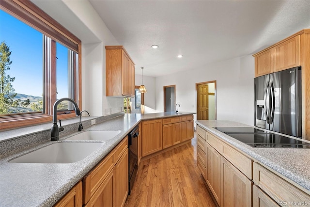 kitchen with recessed lighting, a peninsula, a sink, light wood-style floors, and black appliances