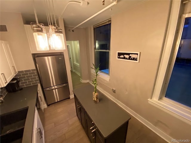 444 17th St Unit 508, Denver, CO 80202 - kitchen with freestanding refrigerator, backsplash, white cabinets, and wood finished floors